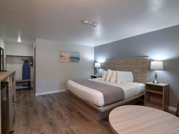 A modern hotel room with a king bed, two nightstands, a round table, and a small desk area, bright and inviting.